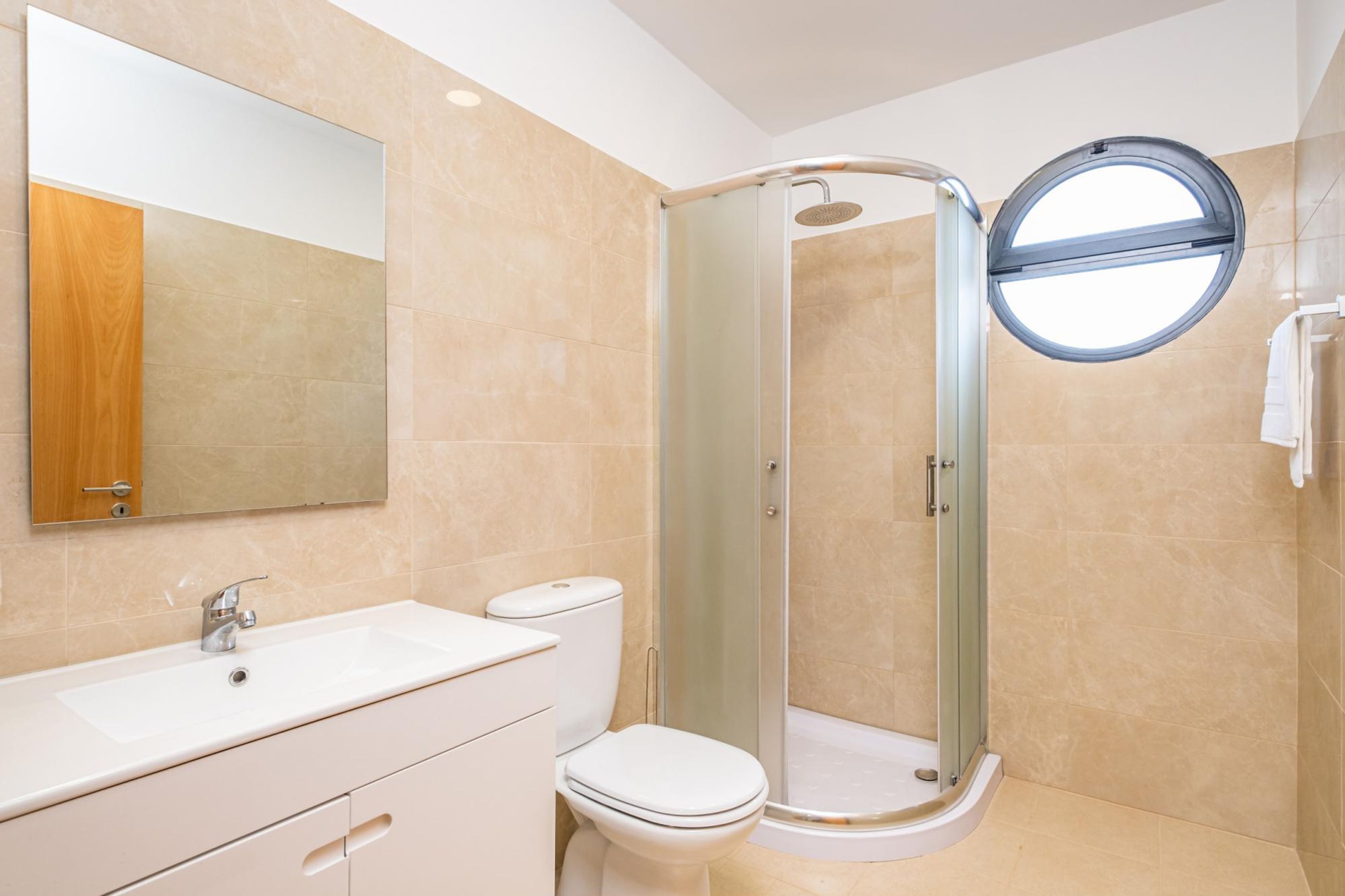 A modern bathroom with a glass-enclosed shower, a sink, and a toilet.