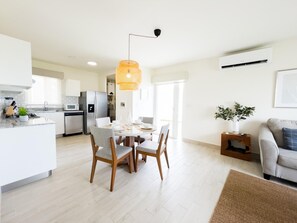 Une cuisine moderne avec un coin repas, un salon doté d’un canapé et une petite table d’appoint agrémentée d’une plante.
