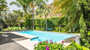 A swimming pool surrounded by lush greenery and palm trees. - Quinta da Tia Briosa Casa da M e II by Homie (Ponta do Sol)