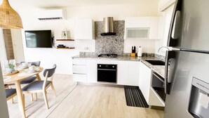 Eine moderne Küche mit weißen Schränken, einer Edelstahl-Dunstabzugshaube, einem Einbauofen und einem Kühlschrank.