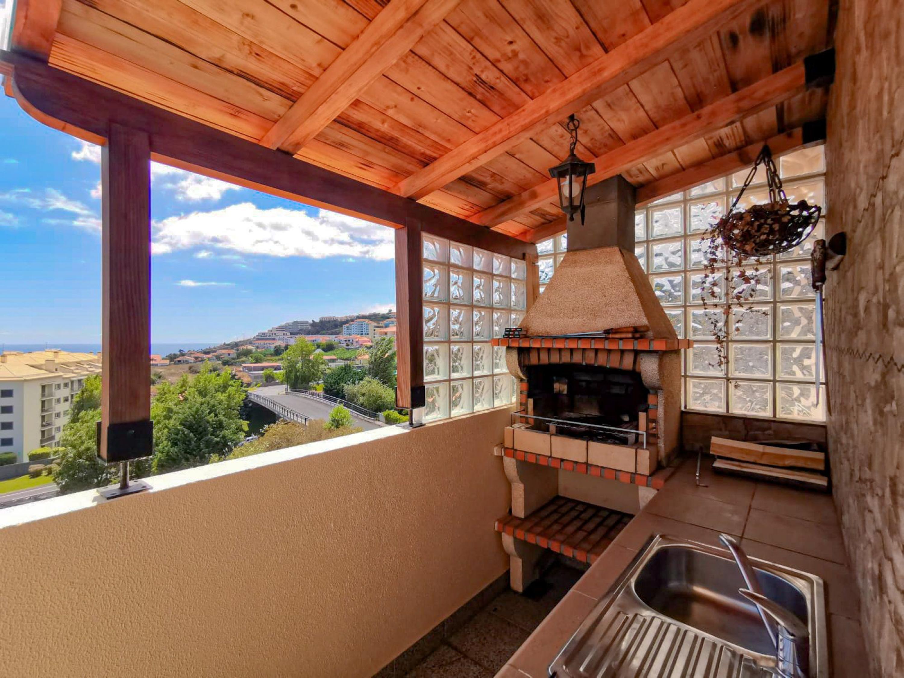 A kitchen with a brick oven, a window with a view of a town, and a hanging light fixture.