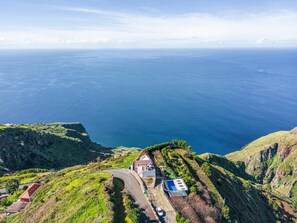 Une propriété située sur la côte, avec une route sinueuse, une piscine et une vue sur l’océan.