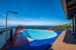 Ein Schwimmbecken mit freiem Blick auf das Meer und ferne Berge.