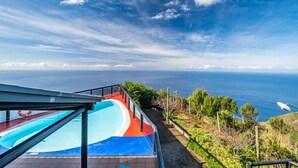 A pool area with a clear view of the ocean and a distant coastline. - Ocean Panorama House by Homie (Calheta)