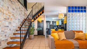 A modern living room with a staircase, a dining area, and a kitchen visible through an open door. - Ocean Panorama House by Homie (Calheta)