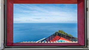 A framed view of a staircase leading to a balcony overlooking a vast ocean with distant islands. - Ocean Panorama House by Homie (Calheta)