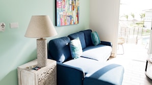 A living room with a blue sofa, a lamp, and a colorful abstract painting on the wall. - Residences C14-1d in Chame (Punta Chame)