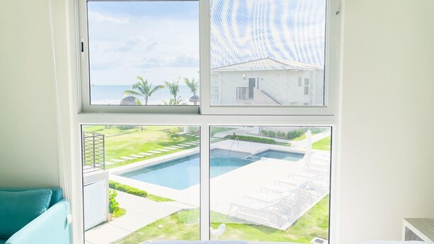 A room with a large window overlooking a pool and a grassy area. - Residences C14-1d in Chame (Punta Chame)