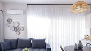 Un salon moderne avec un canapé bleu foncé, une table basse ronde en bois et un coin repas comprenant une table et des chaises aux couleurs sombres.