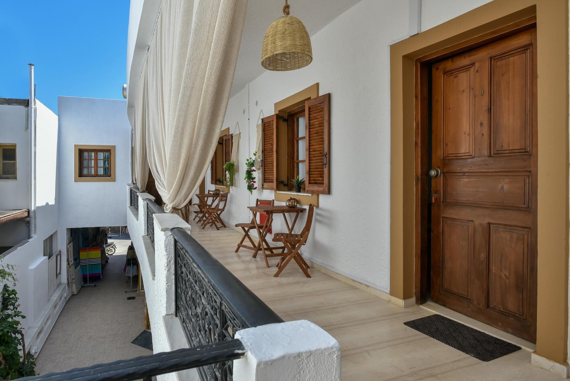 Ein Balkon mit Holzmöbeln, einer großen Holztür und einer hängenden Leuchte.