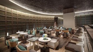 Un espace de détente moderne, doté de différents types de sièges, d’un plafond à motifs et d’un grand mur orné d’un décor en forme de quadrillage.