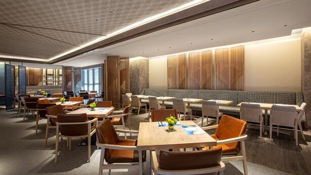 A modern dining area with wooden panel walls, a central seating area, and tables with chairs. - Wyndham Sun Moon Lake (YUCHI TOWNSHIP)