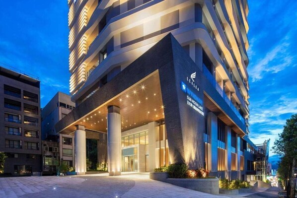 A modern hotel with a prominent entrance, large columns, and a well-lit facade.