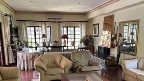 A spacious living room with a large wooden coffee table, beige sofas, and a patterned rug. - A Boutique Lodge Situated in a Serene Environment - 2030 (Harare)