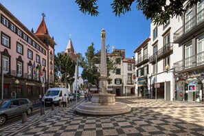 A plaza with a central monument, surrounded by buildings with commercial establishments.
