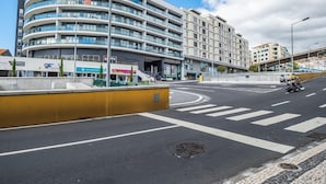 Un edificio de varios pisos con fachada curva, un paso de peatones y una calle con una motocicleta.