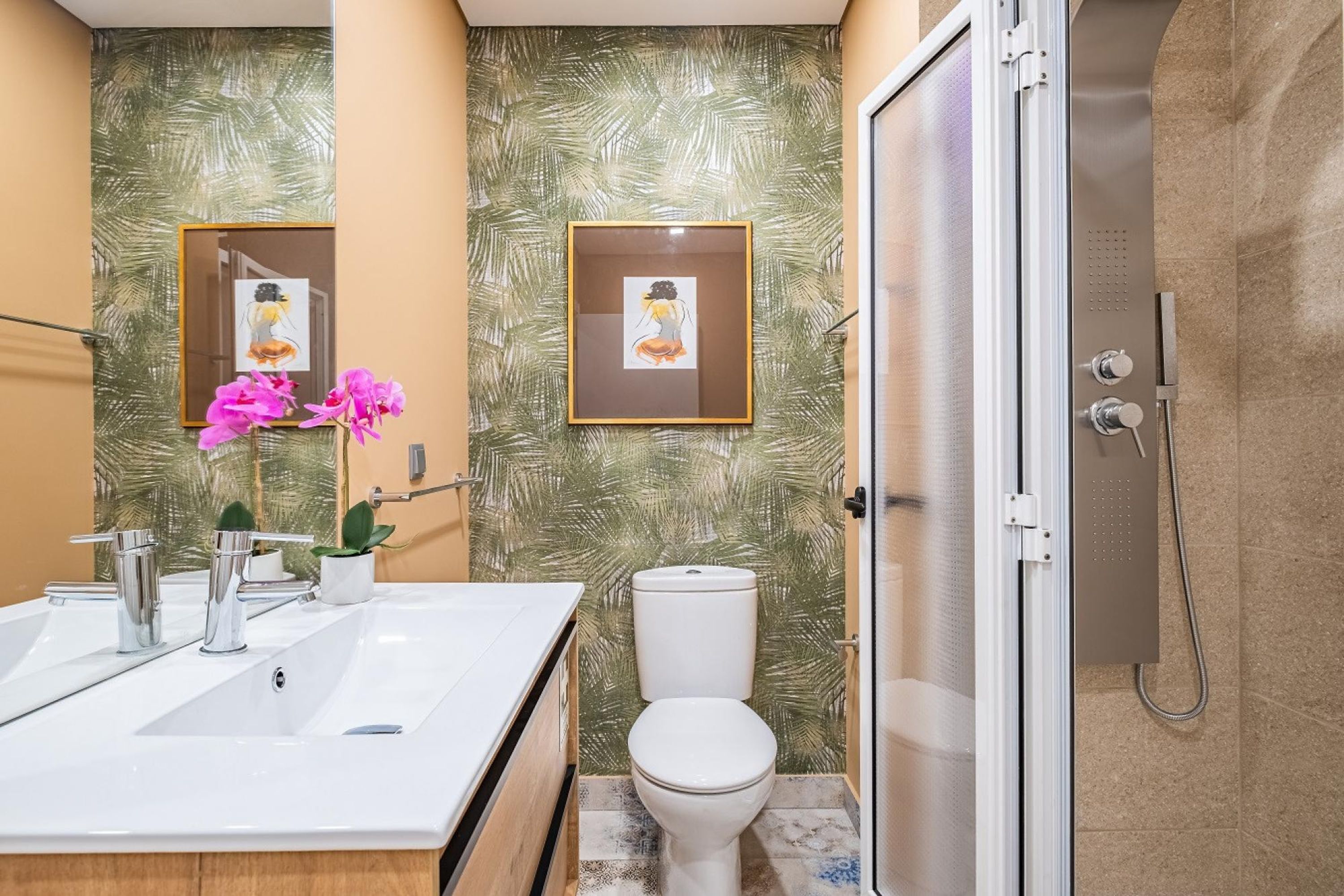 Een badkamer met twee wasbakken, toilet en douche.