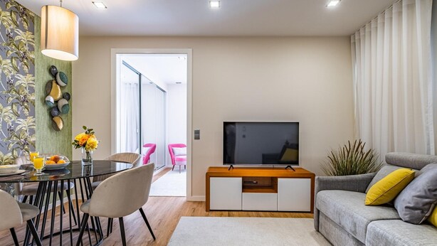 Una sala de estar moderna con comedor, televisor de pantalla plana y sofá con cojines.