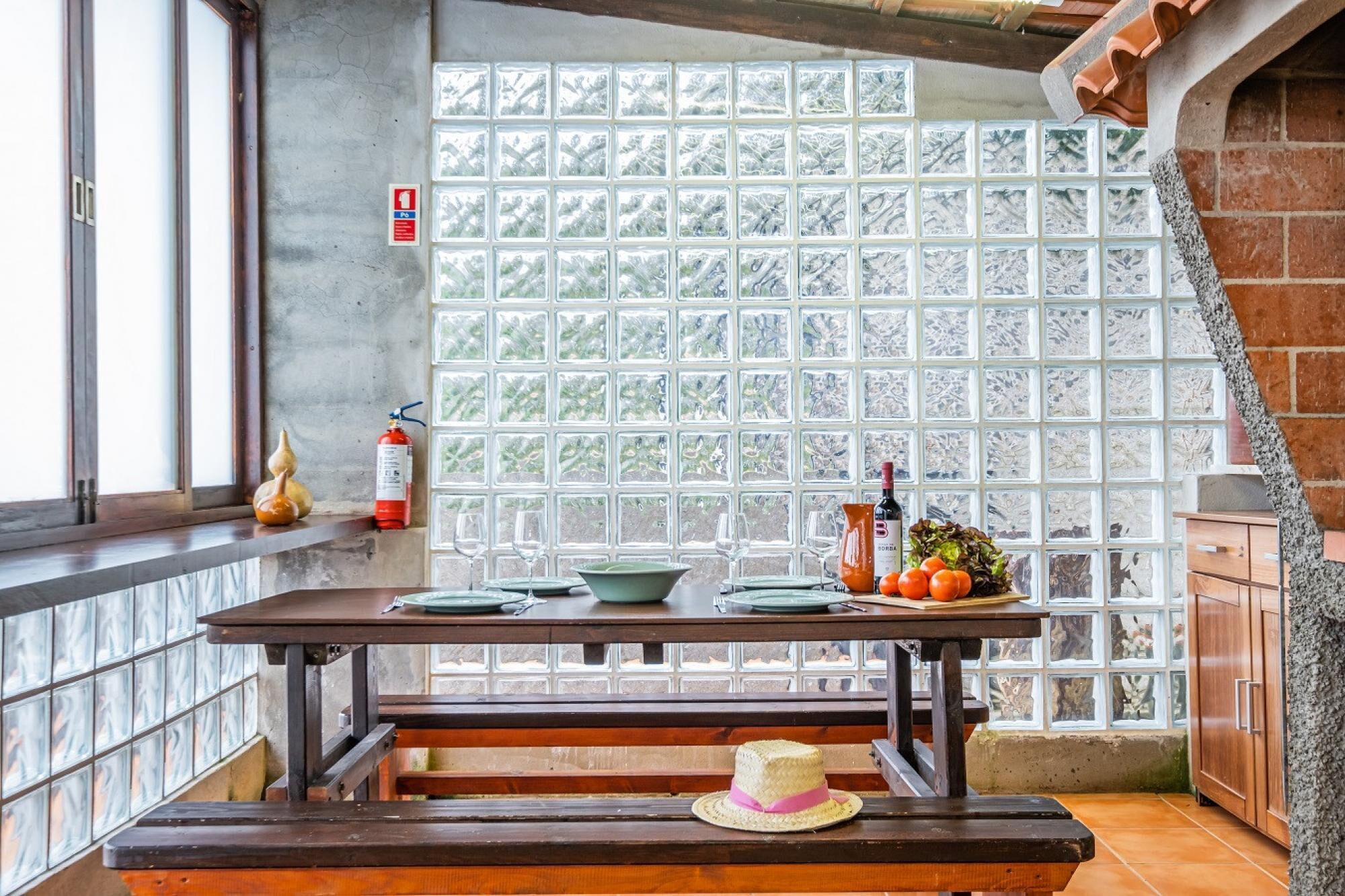 A dining area with a table set for two, a fire extinguisher, and a window with frosted glass panels.