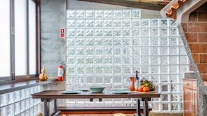 A dining area with a table set for two, a fire extinguisher, and a window with frosted glass panels. - King Shelter by Homie (Porto Moniz)