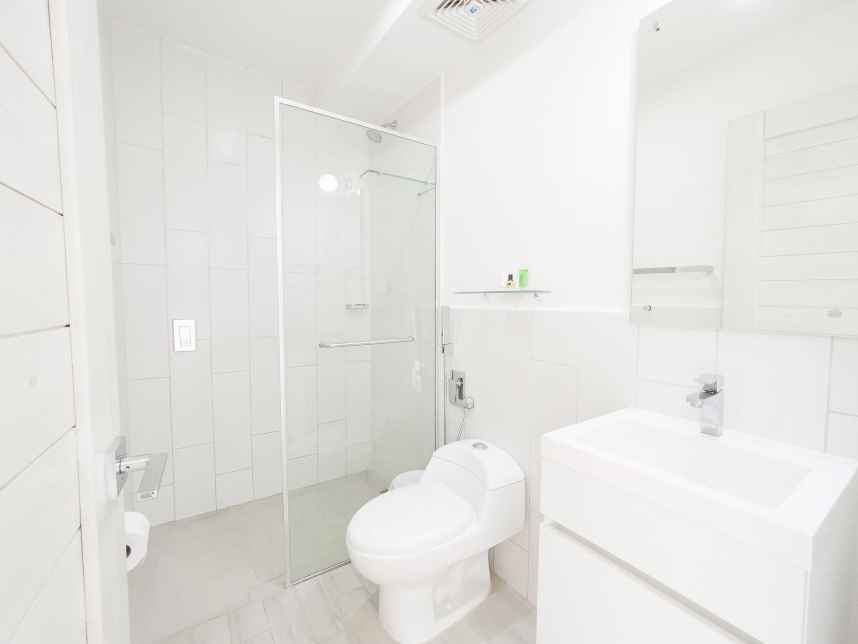 A modern bathroom with a glass shower enclosure, a toilet, and a sink with a mirror above it.