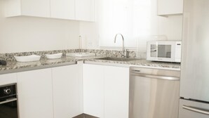 A modern kitchen with white cabinets, a granite countertop, a built-in microwave, and a dishwasher. - Residences C7-pbb in Chame (Punta Chame)