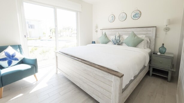 A bedroom with a large bed, a chair, a nightstand, and a wall with decorative plates. - Residences C7-pbb in Chame (Punta Chame)