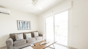 A modern living room with a grey sofa, a wooden coffee table, and a ceiling fan. - Residences C7-pbb in Chame (Punta Chame)