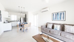 A modern living room with a grey sofa, wooden coffee table, and a dining area with a table and chairs. - Residences C7-pbb in Chame (Punta Chame)