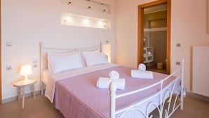 A neatly arranged bedroom with a bed, bedside lamps, a mirror, and a small table with a lamp. - Villa Eolos With Private Pool (Malevizi)