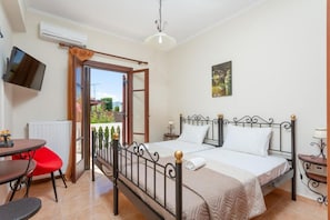 Quarto com cama, escrivaninha, cadeira e televisão.