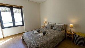 A bedroom with a bed, two bedside tables, a lamp, and a waste bin. - Belle Vue Apartment by Acasadascasas (Mafra)