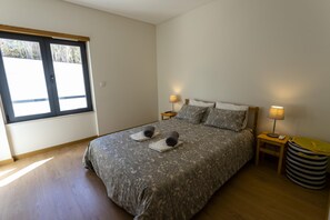 Ein Schlafzimmer mit einem Bett, zwei Nachttischen, einer Lampe und einem Mülleimer.