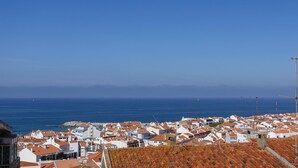 A coastal town with white buildings and red-tiled roofs, a clear blue sky, and the sea in the background. - Belle Vue Apartment by Acasadascasas (Mafra)