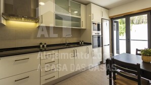 A modern kitchen with white cabinets, a black countertop, and a built-in oven. - Belle Vue Apartment by Acasadascasas (Mafra)