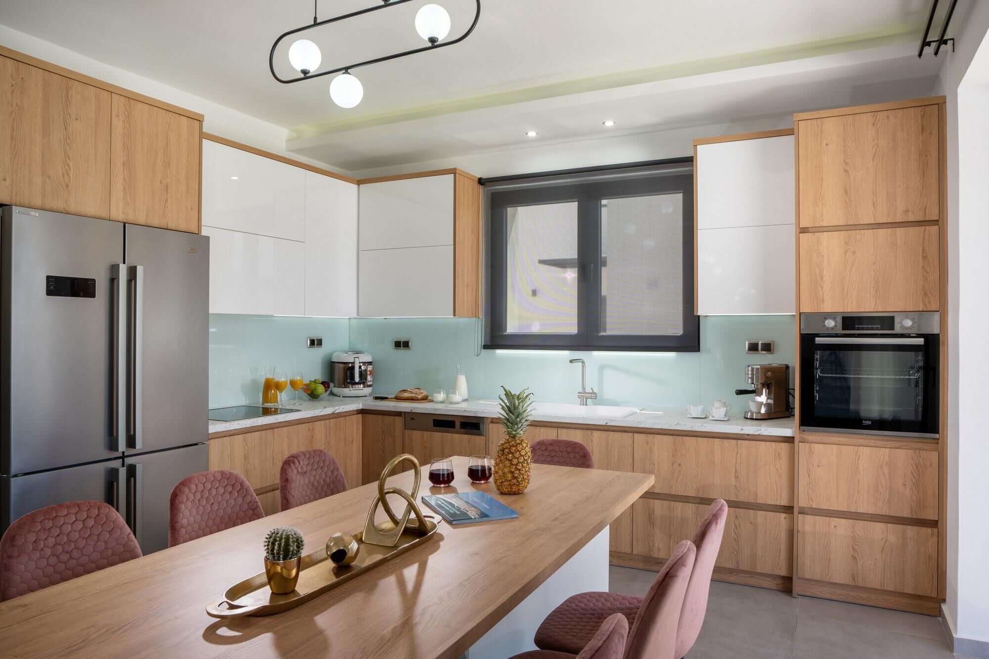 A modern kitchen with wooden cabinets, stainless steel appliances, and a central island with seating.