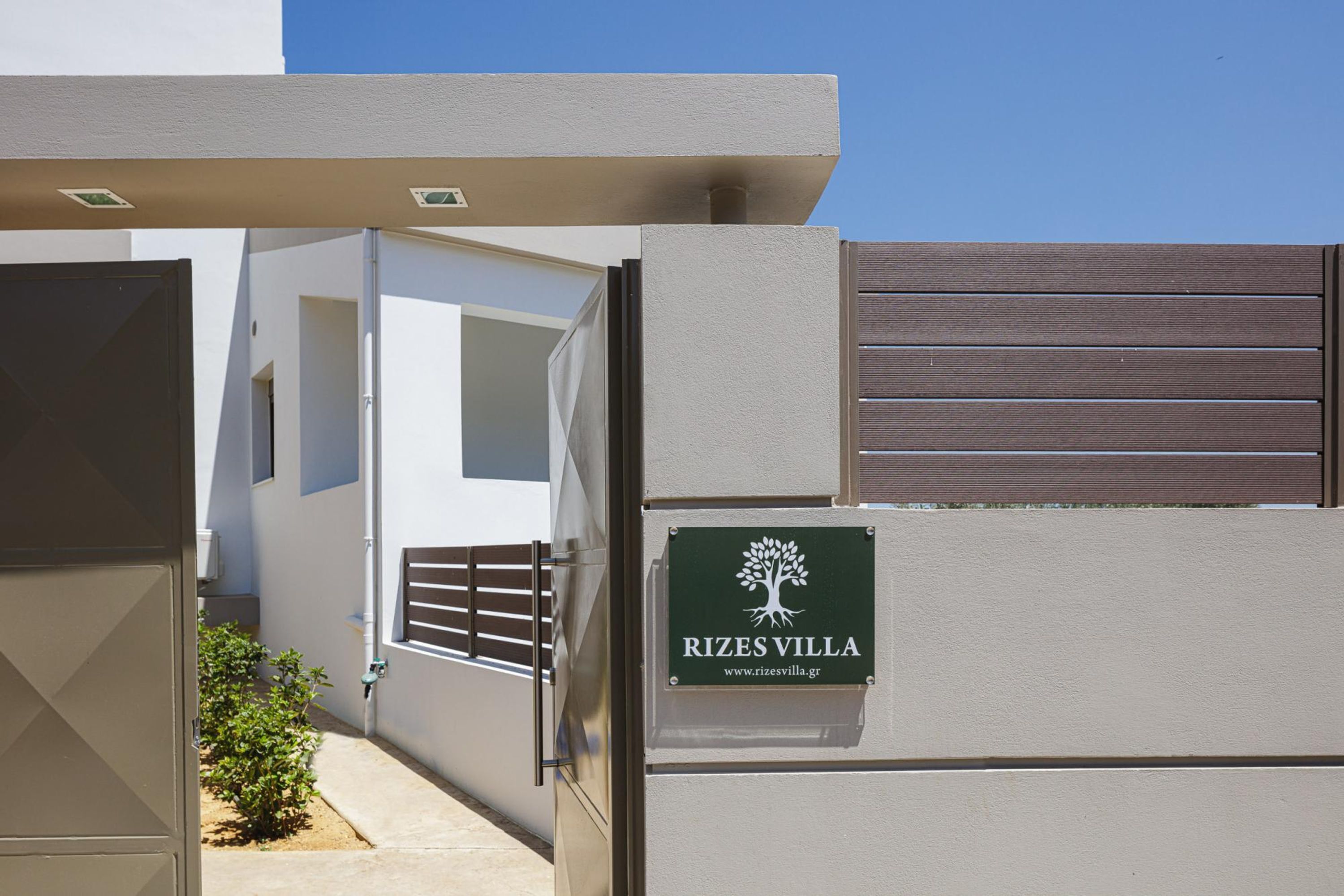 A gated entrance to Rizes Villa with a sign displaying the name and website.