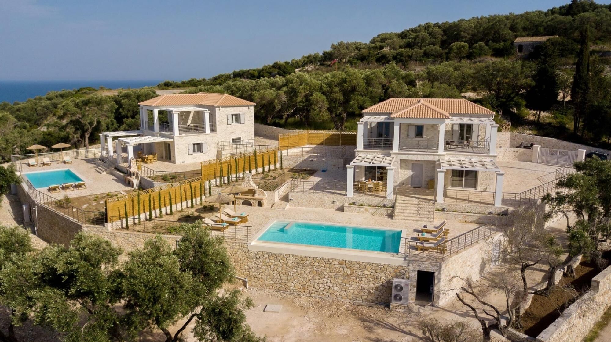A two-story villa with a swimming pool, outdoor seating, and a view of the sea.