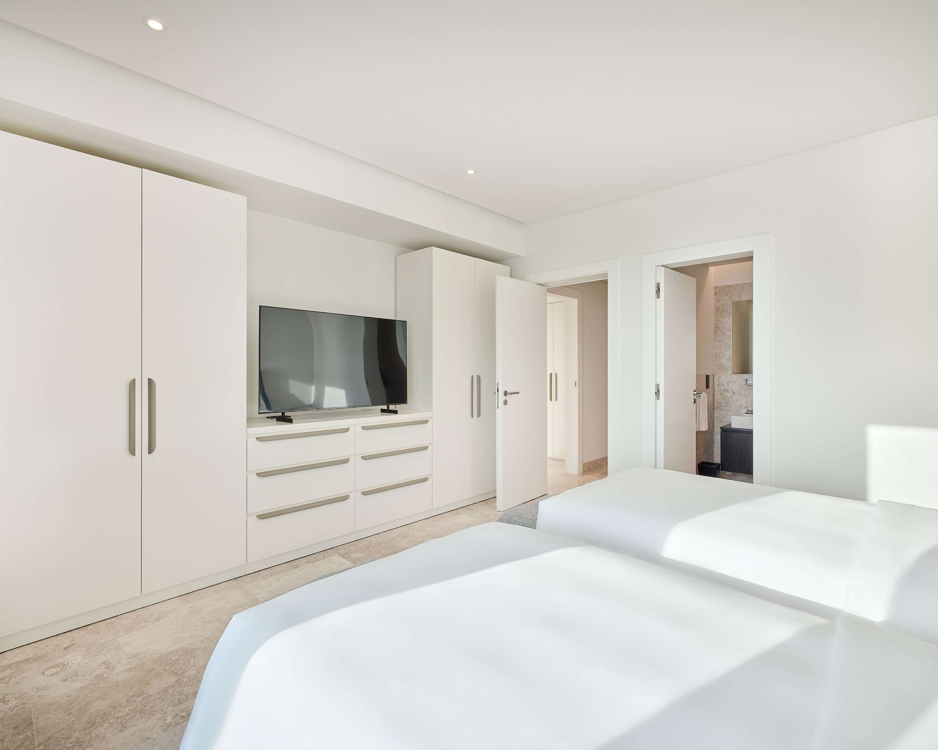 Une chambre moderne dotée d’une grande armoire, d’un téléviseur à écran plat et d’un design minimaliste.