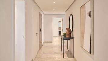A hallway with a marble floor, white walls, and a black console table with decorative items.