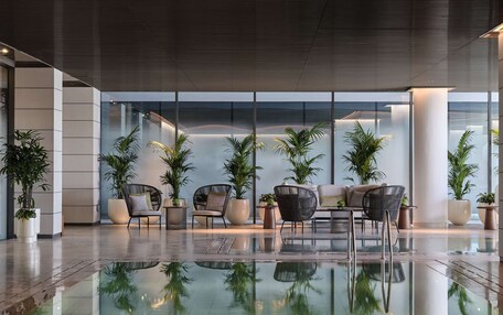 A modern indoor pool area with lounge chairs and potted plants.