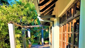 A stone-paved pathway leading to a building with a covered entrance and a garage with large windows. - Cozy 3 Bedroom House With Unique Bathrooms - 2084 (Bulawayo)