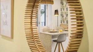 A dining area with a round mirror, a whiteboard with text, and a table with chairs. - Funchal Tropical - Hurricane Plant by Homie (Funchal)