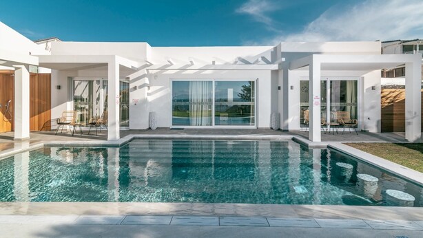 A modern house with a swimming pool, large glass doors, and a pergola.