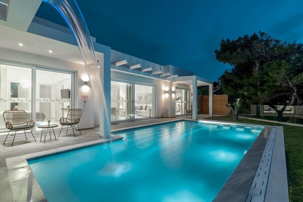 A modern house with a swimming pool, large windows, and a patio area.