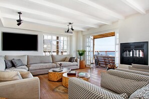 Relax in this stylish living room with a large flat-screen TV, comfortable sofa, and balcony offering a sea view.