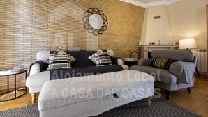 A living room with a brick wall, a round mirror, two sofas, a side table, and a lamp.