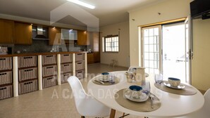 A spacious kitchen with modern appliances, a dining area with a round table set for four, and a large window providing natural light.