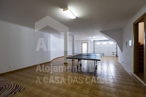 A spacious room with a large table, white walls, and a tiled floor.