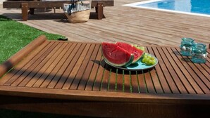 A stone villa with a pool, a wooden deck, and a lounge area with a sunbed and a table with fruit and drinks. - Villa Prima - With Private Heated Pool (Rethymno)